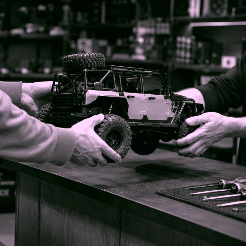 Dos personas entregando un auto RC para servicio técnico